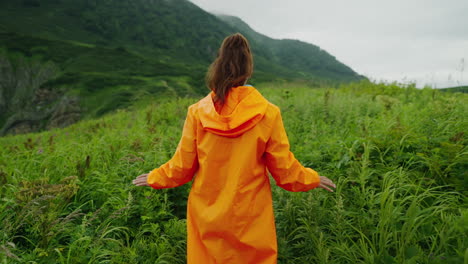 woman hiking in mountains with orange raincoat