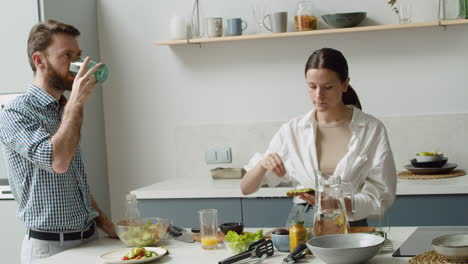 mujer bonita condimentando una tostada de aguacate y dándosela a su marido