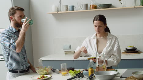 pretty woman seasoning an avocado toast and giving it to her husband