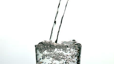 agua que se vierte en un vaso y se desborda sobre un fondo blanco