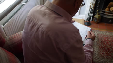 a lonely senior man opening a debt letter