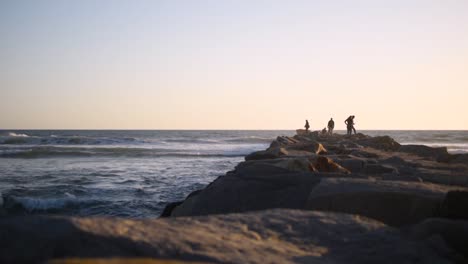 beautiful, calm, sunset in san diego, shooting down a jetty with people and waves crashing alongside it