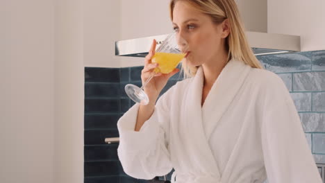 Blonde-Frau-Trinkt-Orangensaft-In-Der-Küche.