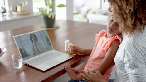 Madre-Birracial-E-Hija-Enferma-Teniendo-Videollamada-Portátil-Con-Doctora,-Cámara-Lenta