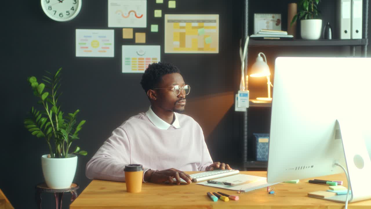 Young African American Man Working on Computer at Desk in Office