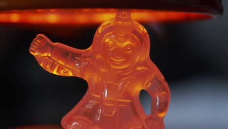 close-up of a translucent figure with glowing orange hue, capturing the reflection and detail of a playful character as it melts gently under heat