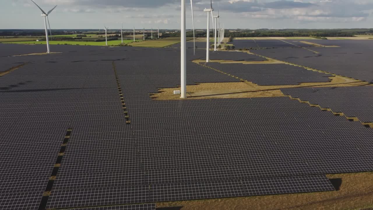 덴마크 벰베에서 화창한 날 들판에 있는 풍력 터빈 주변의 태양광 모듈