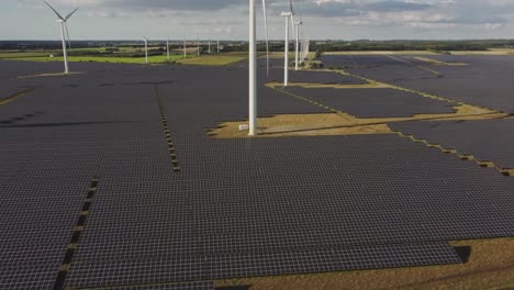 Photovoltaic-Modules-Around-The-Wind-Turbines-In-The-Field-On-A-Sunny-Day-In-Vemb,-Denmark