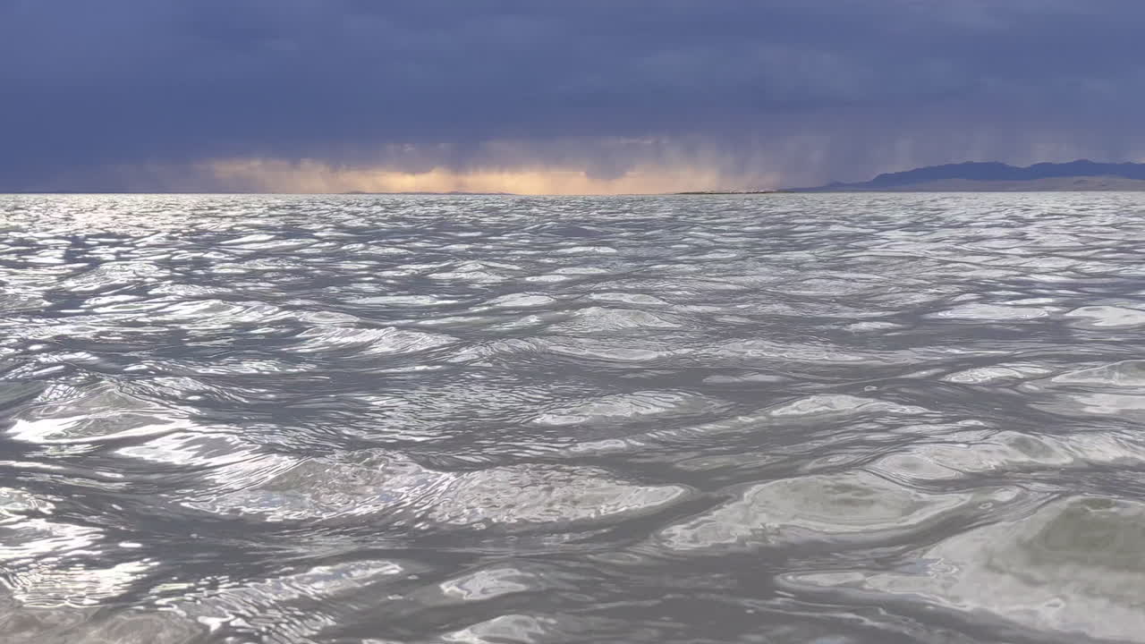 일몰 동안 유타의 소금 호수 표면에 물 잔물결