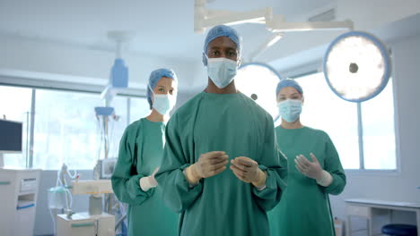 Portrait-of-three-diverse-male-and-female-surgeons-in-operating-theatre,-slow-motion