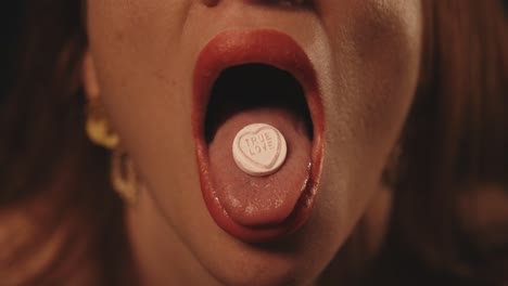 woman with open mouth and tongue eats a pill or tablet 50fps