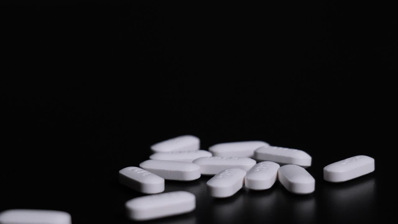 Pillole su prescrizione che fuoriescono da una bottiglia su uno sfondo scuro