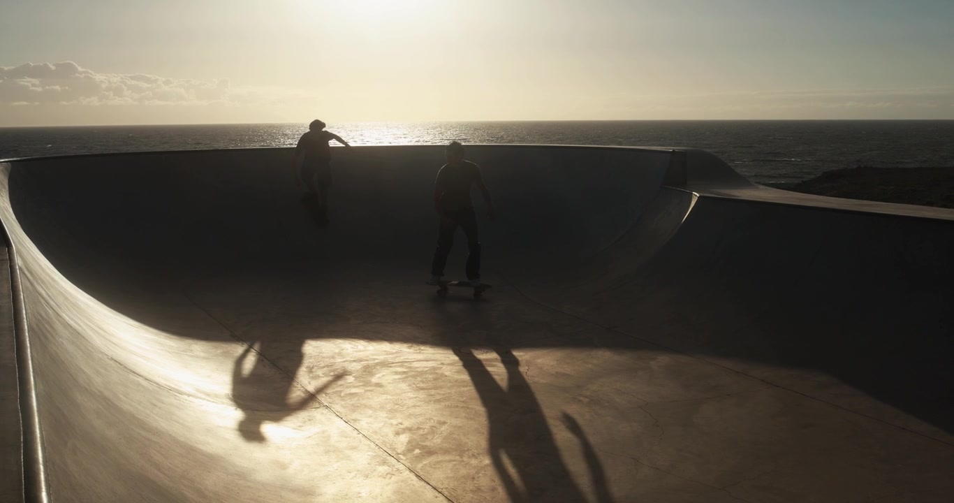 Silhouetted Skaters in a Coastal Skatepark at Sunset
