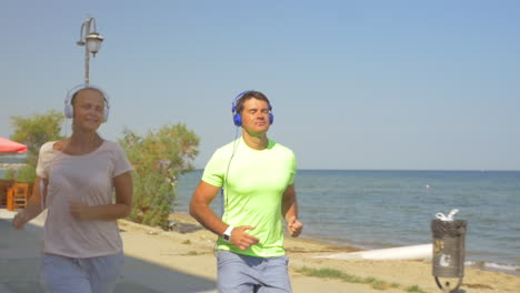 Man-and-woman-running-with-music-along-seafront