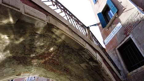 person riding on a gondola boat passing under the bridge in venice, italy