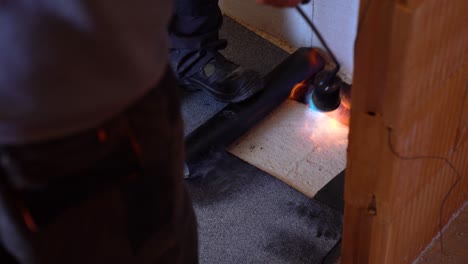 flame torch used to seal bitumen sheet on indoor surface during insulation process