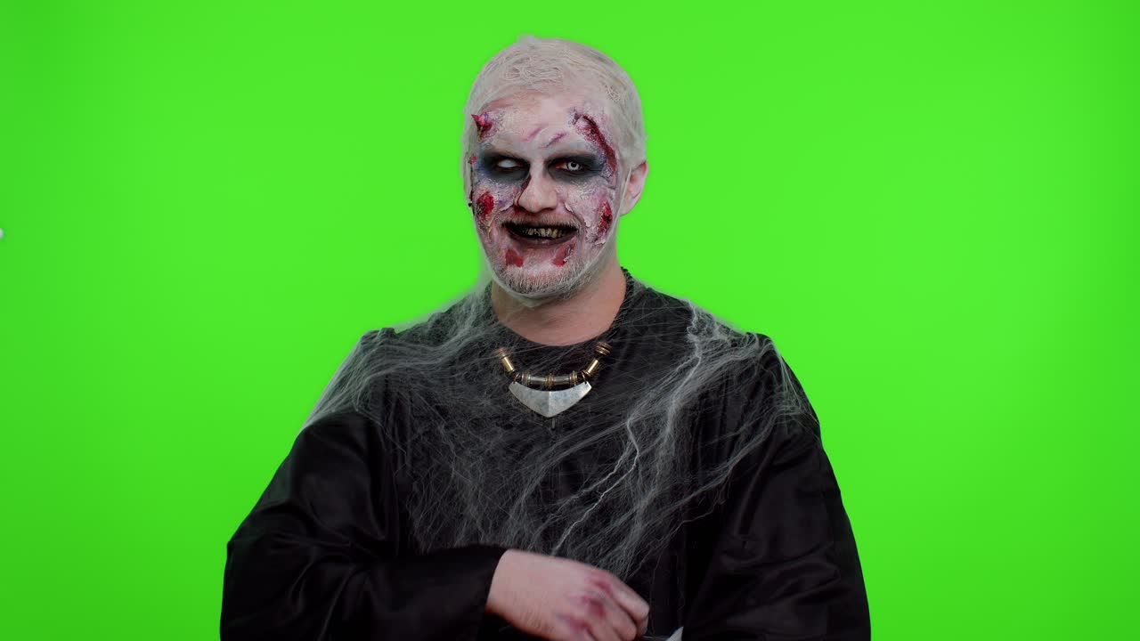 Uomo inquietante e sorridente, zombie di Halloween, che fa smorfie, guarda la telecamera e sorride in modo terrificante con i denti sporchi.