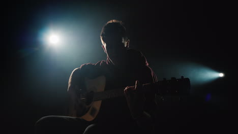 a young musician plays the guitar on the stage in the spotlight 4k video