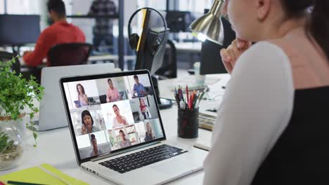 mujer caucásica teniendo una videoconferencia con colegas de oficina en una computadora portátil en la oficina