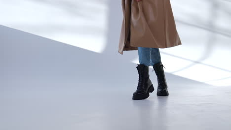 woman walking in a beige coat and black boots