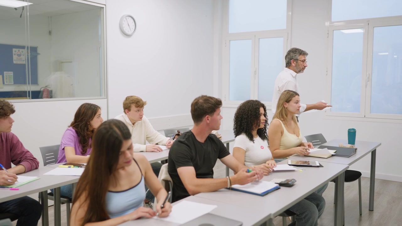 Insegnante maschio distribuisce fogli agli studenti in un'aula moderna