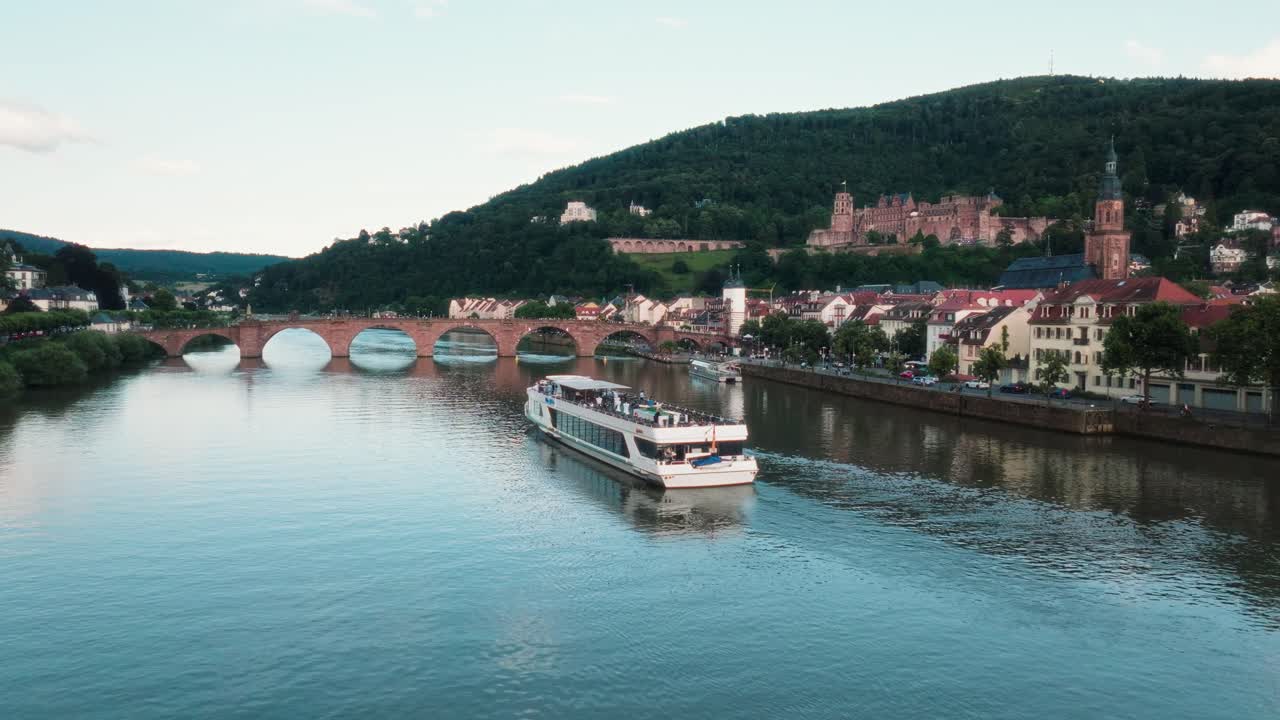 Cruise boat sailing on the Neckar river near famous arch bridge in Heidelberg, Drone view