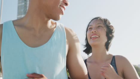 happy biracial couple running on promenade, in slow motion