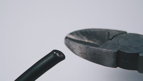 cutting-black-wire-with-nippers-on-empty-light-background