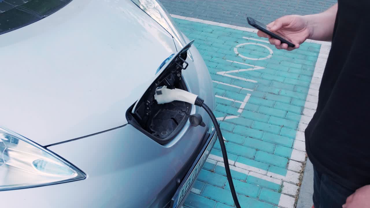 電気自動車の充電プロセス - 電気自動車が充電するハッチの下のショット - 電気車の充電ハッチは自動的に開きます - 男性の手が勃起した車を入します