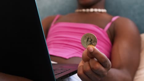 person holding bitcoin coin while using a laptop