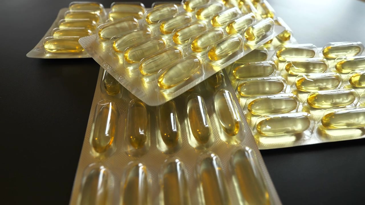 Capsule di gelatina gialle in blister su superficie scura.