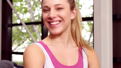 fit woman smiling to camera while people doing some stretching