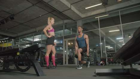 la cámara hace zoom en el monitor de una mujer caucásica y un hombre atlético afroamericano en el gimnasio.