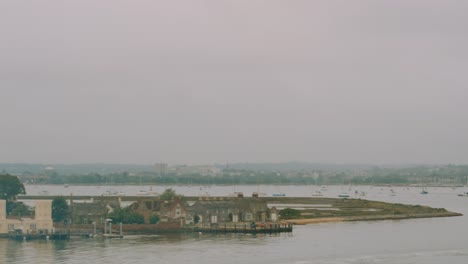 panning shot revealing brownsea island castle with small boat travelling by with light fog in early morning 4k