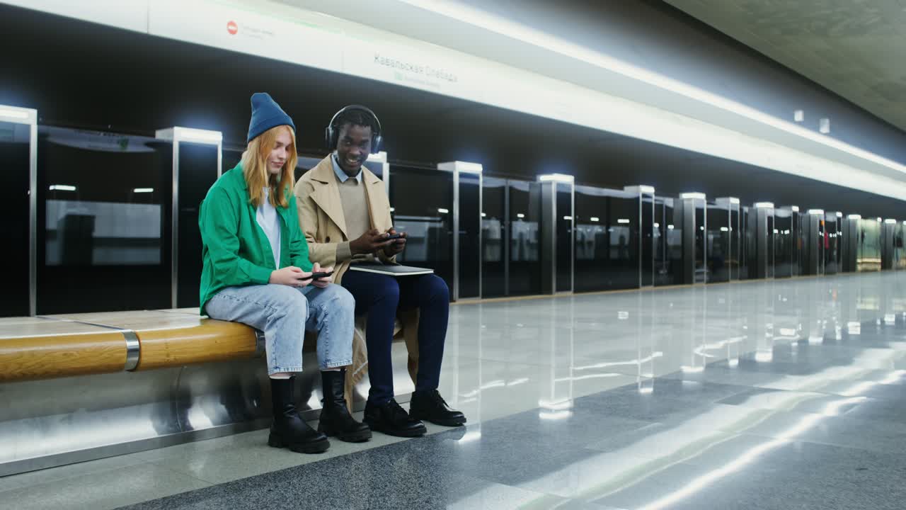 People using smartphones and laptops on a subway platform