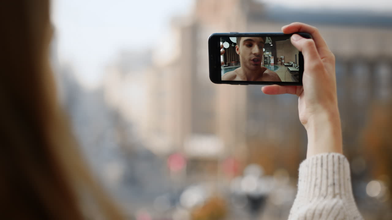 Homem feliz fazendo videochamada com a namorada usando o celular. Close-up de mulher segurando o celular