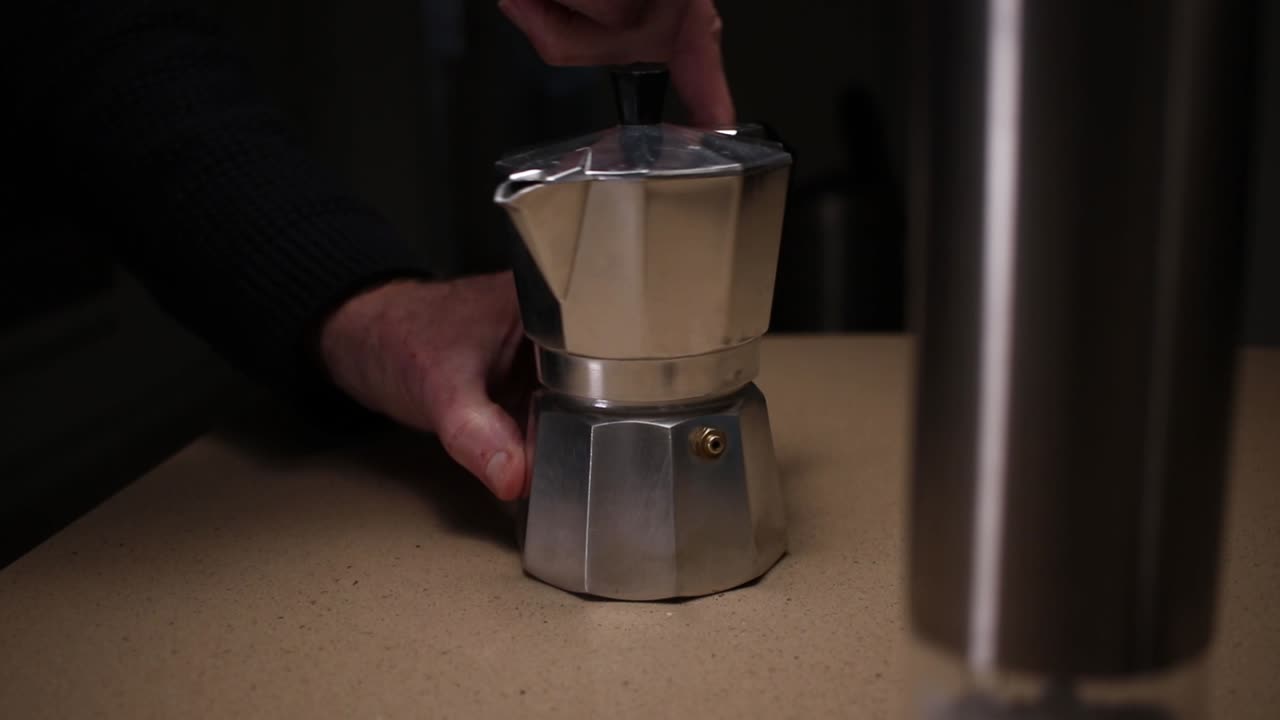 Dolly footage of the top section being screwed to the base section of a Moka stove top Italian espresso coffee maker.