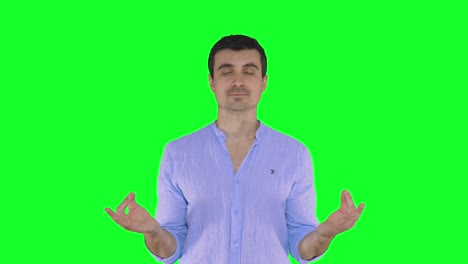 A-handsome-young-man-in-a-blue-shirt-meditating-and-exercising-yoga-with-his-hands,-green-screen