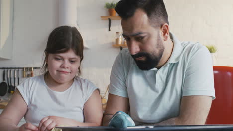 father showing botched cookies to daughter medium closeup of a father showing botched cookies to daughter