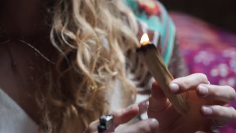 primer plano de un palo de incienso encendido y sostenido por una mujer espiritual consciente ecológica que lo sopla