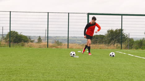 soccer player in orange jersey practicing on field, preparing for kick