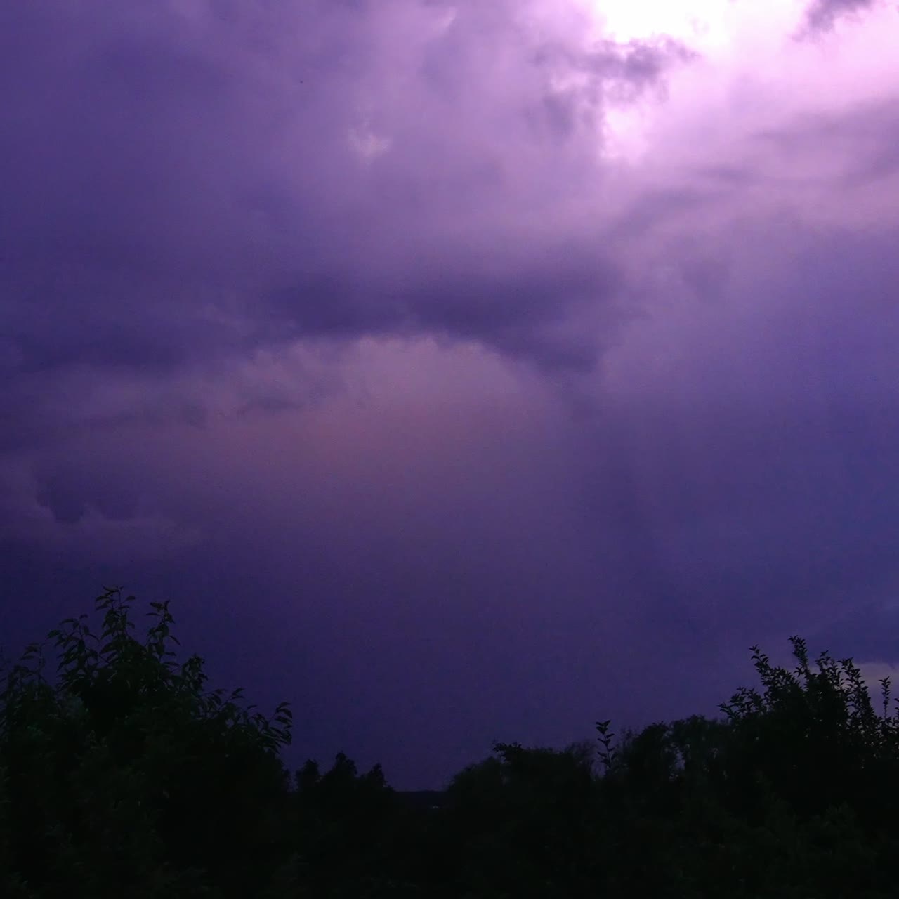 Storm and lightning in the rural countryside. Tops of trees swaying in the wind. Night skies lit by thunderstorm