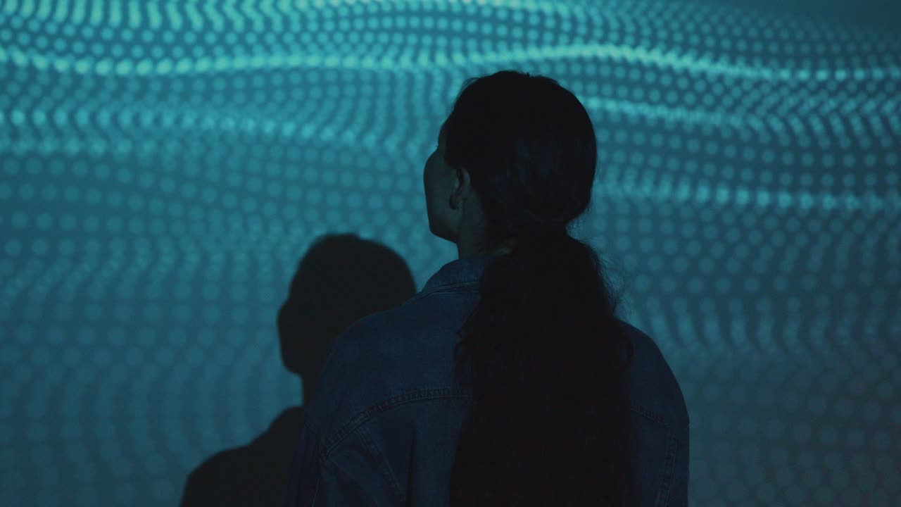 벽 1에 모양의 투영과 함께 몰입 예술 전시를 방문하는 여성의 실루