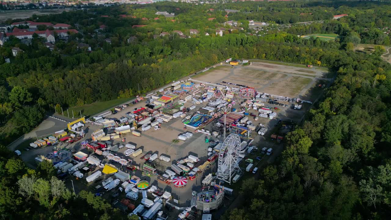 숲으로 둘러싸인 야외 숲, 놀이기구와 가판대가 있는 놀이공원, 카니발. 드론 상승