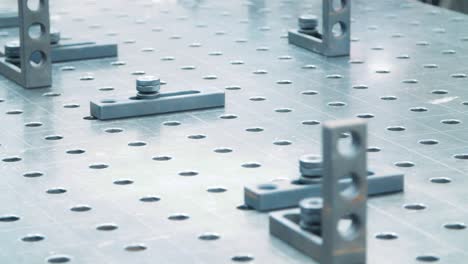 Fasteners-on-working-surface-of-industrial-unit.-Metallic-plate-with-holes