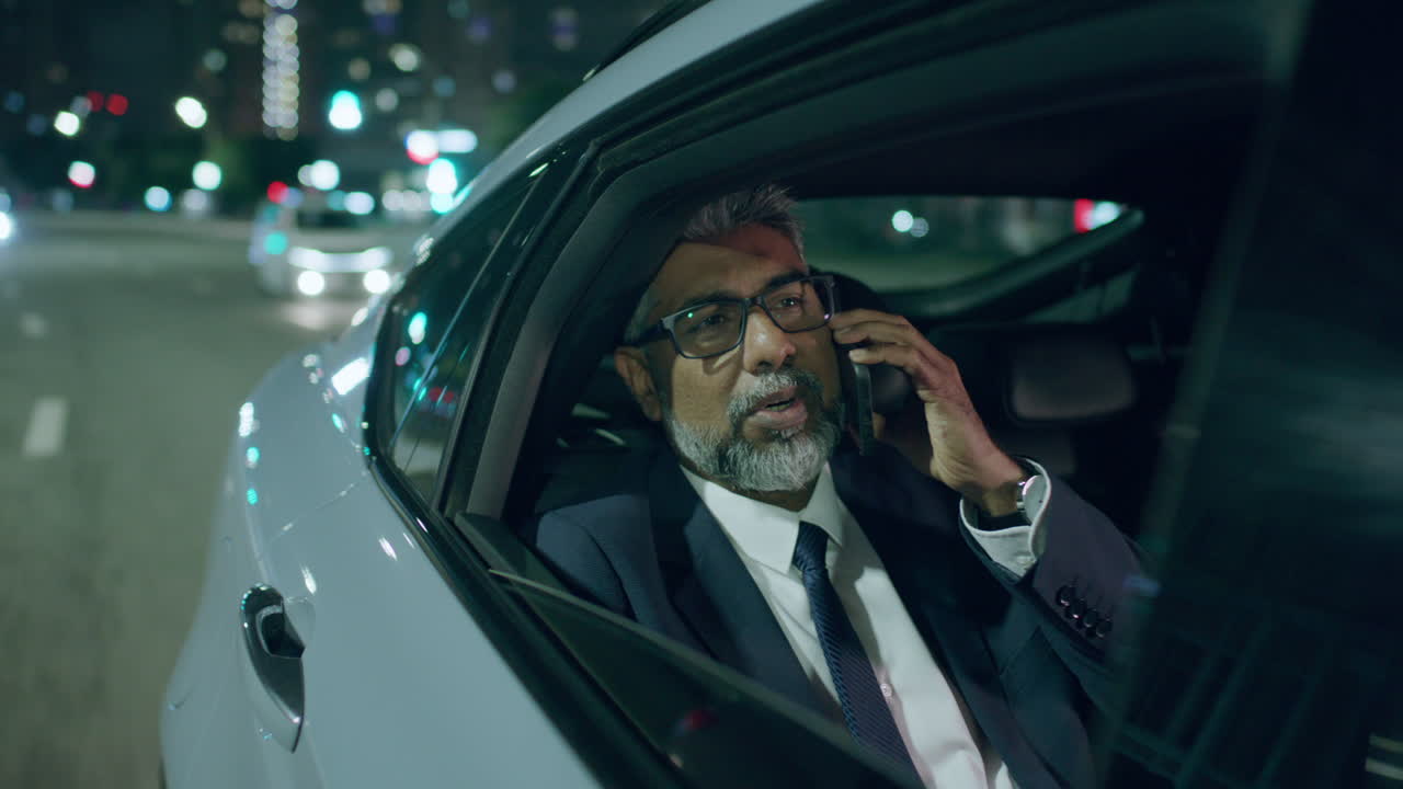 Senior Business Executive Having Phone Conversation in Car during Night Ride
