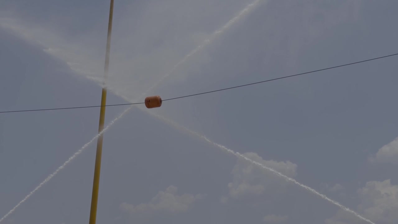 Ripresa al rallentatore di due getti di idranti antincendio ad alta pressione che mirano e colpiscono una boa bersaglio galleggiante durante un'esercitazione competitiva di addestramento alla sicurezza antincendio industriale.