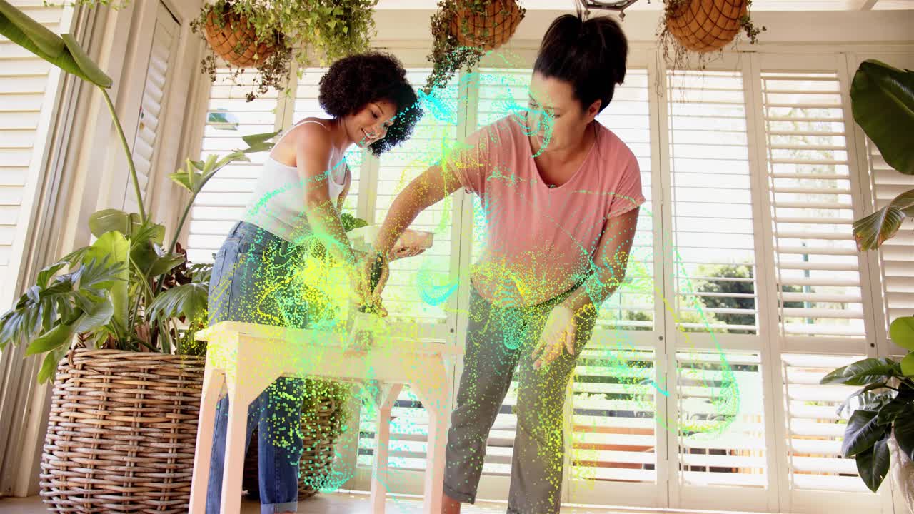 Two women placing table, dipping brushes and painting for DIY decor while particles rising around