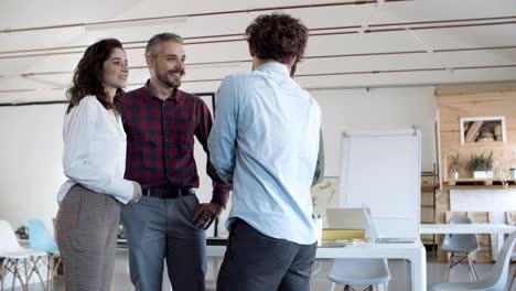 cheerful colleagues shaking hands and talking