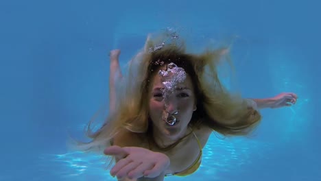 pretty blonde swimming towards camera and blowing kiss